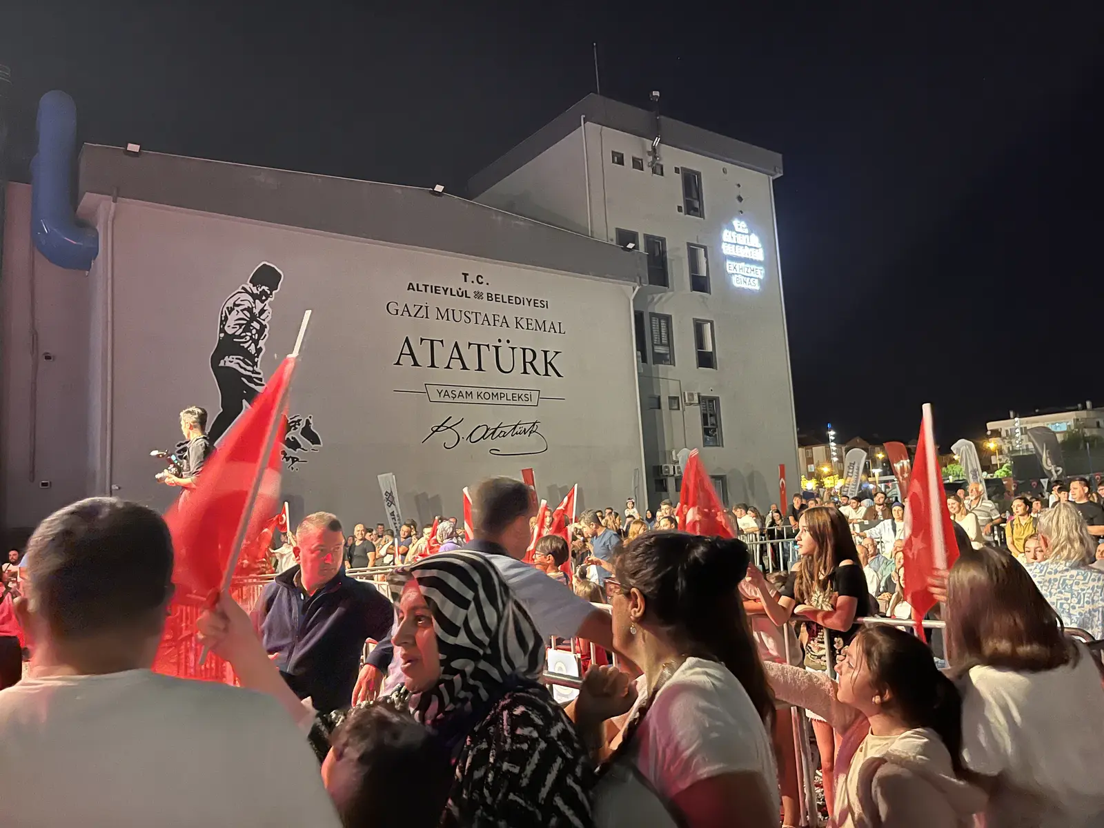 Altıeylül Belediyesi Yaşam Kompleksi tabelası ve bayraklı kalabalık — okur fotoğrafı